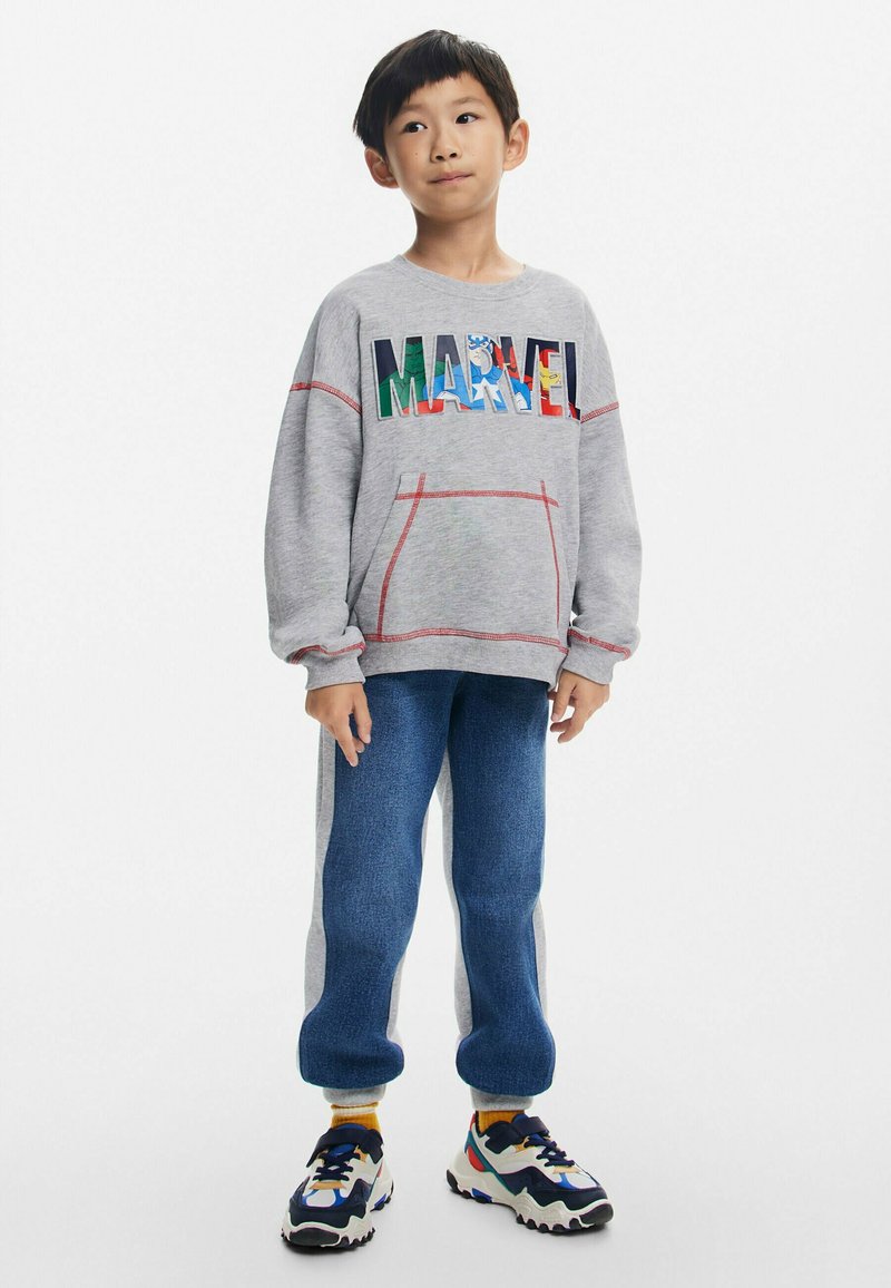 Harmaa huppari, jossa on "MARVEL" -logo, punaiset tikkaukset ja etutasku. Siniset farkkumaista kangasta joggerit, joissa on harmaat sivupaneelit. Värikk�äät lenkkarit.