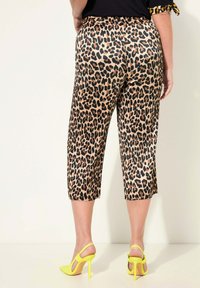 Kalhoty s leopardím potiskem, zkrácené, s elastickým pasem, elegantní látka a hladká textura, doplněné jasně žlutými lodičkami na vysokém podpatku.