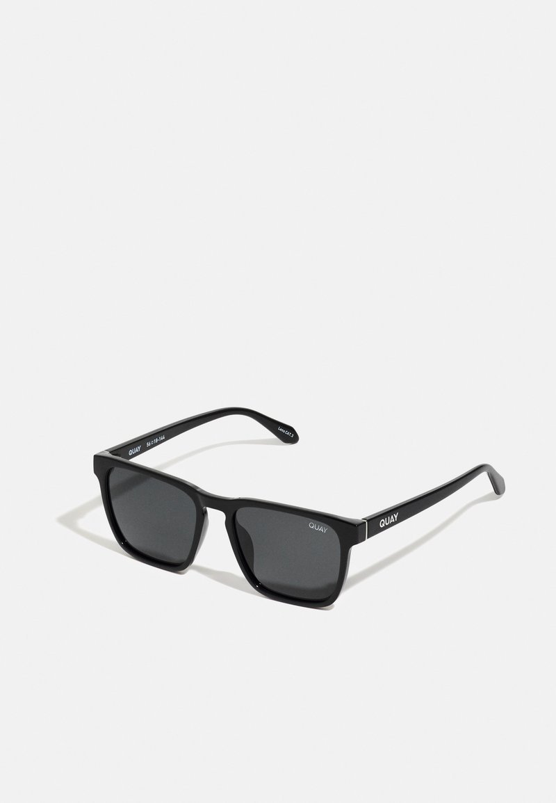 Óculos de sol retangulares pretos com lentes escuras. Feitos de plástico, apresentam uma textura suave e a marca "QUAY" na parte das hastes.