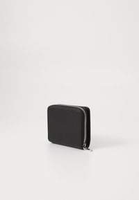 Portefeuille noir zippé avec une texture lisse, de forme rectangulaire et un détail en métal argenté le long de la fermeture éclair. Design compact et simpliste.
