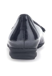 Zwarte patenten leren schoen met een gladde glanzende afwerking, ronde neus en lage rubberen zool. De achteraanzicht toont een lichte hak en een gepolsterde kraag.