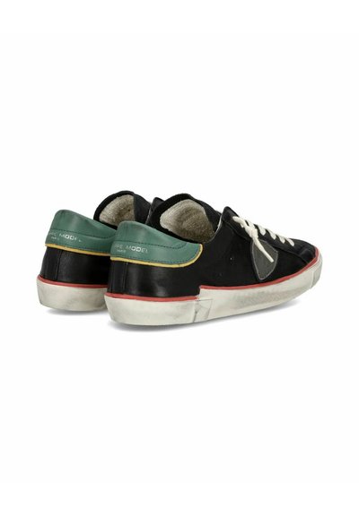 Sorte læder sneakers med en grøn hælkappe, hvide snørebånd, røde detaljer og en tekstureret sål. Åben stil med en polstret inderside.
