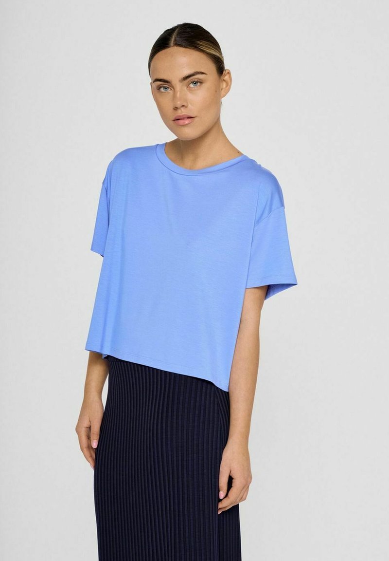 Lyseblå, cropped t-shirt i blødt stof med rund halsudskæring og korte ærmer, parret med en marineblå, ribbet nederdel.