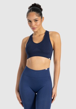 Sostén deportivo azul marino con textura acanalada y un diseño triangular en el frente. Tiene tirantes anchos y una silueta ajustada.