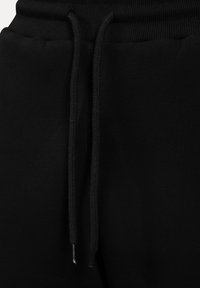 Sorte sweatpants med snoretræk i taljen, ribbet tekstur og subtil glans. Stoffet ser blødt og behageligt ud.