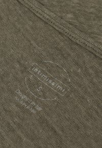 Olivově zelená, texturovaná látka s jemným vzorem. Obsahuje bílou potištěnou etiketu s nápisem "Intimissimi S" a pokyny k údržbě.