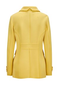 Gelber Blazer mit strukturiertem Design, Reverskragen und sichtbaren Nähten. Das Material ist glatt mit gleichmäßiger Textur. Zwei Knopfakzente an den Ärmeln.