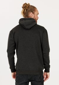 Huvtröja i mörkgrått tyg, mjuk textur, med en känguruficka och ribbade ärmslut. Baksidan visar huvan design.