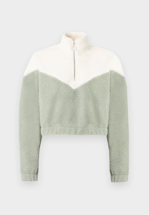 Κοντό φλις μπουφάν με γιακά μισού φερμουάρ σε κρεμ και ανοιχτό πράσινο χρώμα, με σχεδιασμό σε σχήμα βέλους και μαλακό, υφασμένο υλικό.