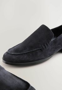 Mocassini in suede di un blu scuro, con dettaglio di cucitura in rilievo e cuciture a contrasto sulla punta, una suola in gomma resistente e una texture liscia.