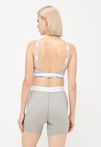 Gray bralette with logoed white straps and matching gray boxer shorts. Both items feature a ribbed texture and a fitted design.