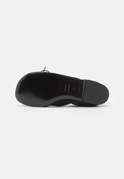 Zapato de ballet negro con upper de cuero suave, punta redondeada y suela de goma flexible. Presenta un diseño minimalista sin adornos.