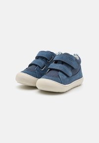 Blue fabric shoes with dual Velcro straps, a soft suede texture, rounded toe, and a white rubber sole. Mesh detailing on the sides.
