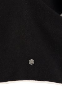 Schwarzer Fleece-Stoff mit glatter Textur, ausgestattet mit einem runden silbernen Logo-Tag. Der untere Rand hat einen kontrastierenden weißen Reißverschlussbesatz.