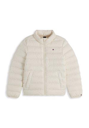 Barn med krøllet blondt hår har en hvid dunjakke over en blå Tommy Hilfiger T-shirt og blå jeans, kigger let til siden.