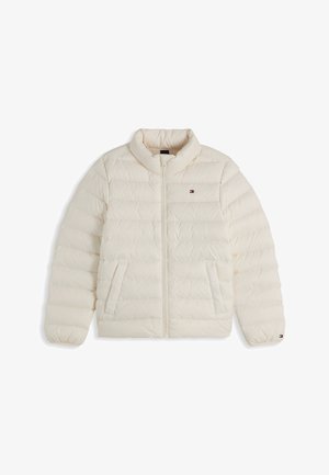 Dziecko o kręconych blond włosach nosi białą pikowaną kurtkę na niebieskiej koszulce z logo Tommy Hilfiger i niebieskich dżinsach, lekko patrzy na bok.
