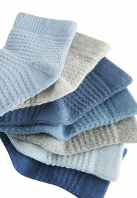Vävda strumpor i nyanser av blått och grått, med ribbade och texturerade mönster i varierande nyanser staplade i en neat ordning.