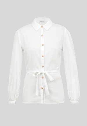 Blouse blanche à manches longues avec col, boutons à l'avant et ceinture à nouer à la taille, présentée sur un fond neutre.
