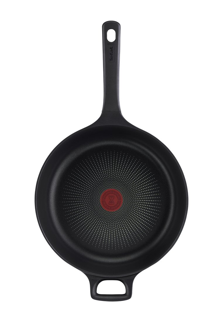 Schwarze antihaftbeschichtete Bratpfanne mit langem Griff und kleinem Schlaufenhenkel, in der Mitte mit rotem Hitzeanzeige-Kreis.