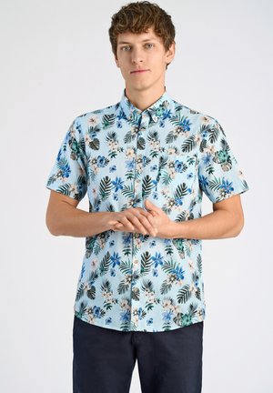 Camisa de botones de manga corta en tejido azul claro con un estampado floral y de hojas tropicales en verdes, azules y beige. Incluye un bolsillo en el pecho.