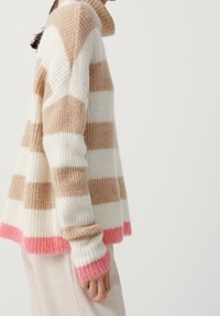 Randig tröja med beige och vita horisontella ränder och rosa detaljer vid fållen och ärmarna. Tillverkad av mjukt, texturerat stickat tyg.