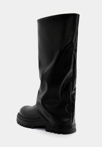 Botas de cuero negro hasta la rodilla con una textura suave, punta redondeada, suela gruesa y diseño recogido en el caño, con un acabado liso.