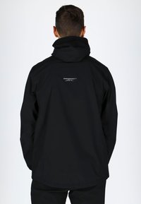 Black jacket with a hood and logo on the upper back. Made of a smooth, lightweight material; features a relaxed fit and longer back hem.