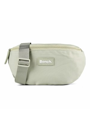 Sac banane en tissu gris clair avec fermeture éclair supérieure et sangle ajustable, marqué "Bench" sur le panneau central avant.