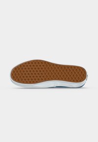 Semelle de chaussure avec une bande de roulement en caoutchouc brun en motif diamant et une semelle intercalaire blanche, vue par dessous sur fond blanc.