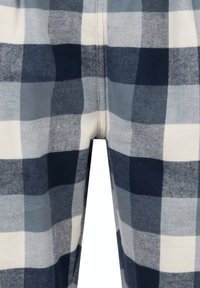 Close-up van een stof met een groot zwart, wit en grijs geruit patroon en zichtbare naadstiksels in het midden.