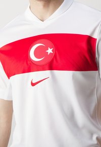 Maillot Nike blanc avec une large bande horizontale rouge, un emblème du drapeau turc au centre et un petit logo Nike rouge en dessous.