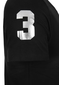 Svart T-shirt med ett silvermetalliskt nummer "3" tryckt på vänster ärm. Tillverkad av mjuk bomullstyg och har en klassisk rundhalsdesign.