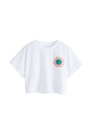 Tricou alb crop cu mâneci scurte, având un mic design de floare spiralată roz și teal pe partea stângă a pieptului.
