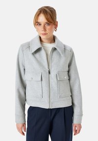 Szara kurtka z mieszanki wełny z zamkiem z przodu, oversize'owy kołnierz, dwie kieszenie naszyte z zatrzaskami oraz ściągacze przy mankietach.