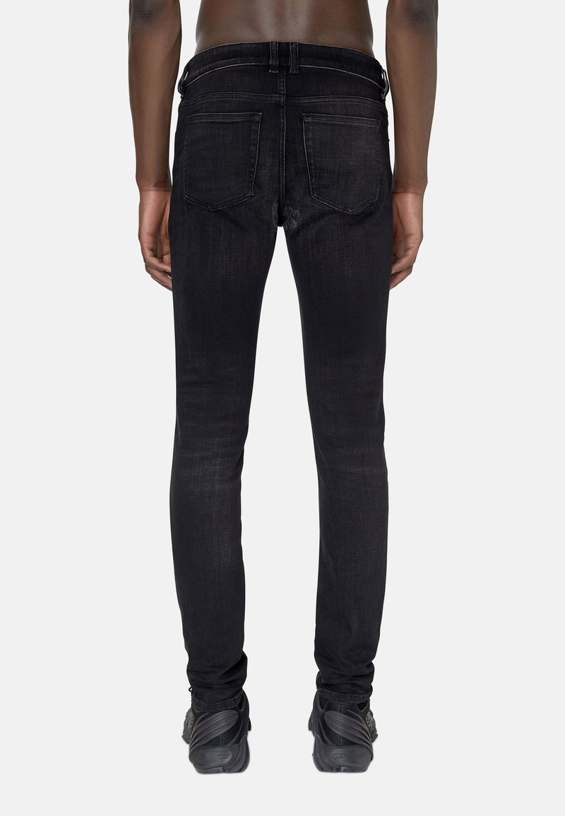 Jean skinny en denim noir avec deux poches arrière, un léger délavage et une finition sombre. Associés à des chaussures de sport noires texturées.