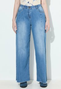 Jeans de pierna ancha en azul claro con dobladillo deshilachado, que cuentan con trabillas para cinturón y cinco bolsillos. Fabricados con tela de mezclilla con una textura ligeramente desgastada.