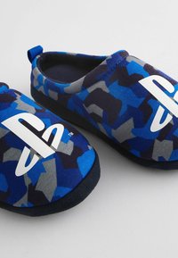 Blå og grå mønstrede slip-on slippers med et hvidt PlayStation-logo, blødt stofoverdel og en sort gummisål.