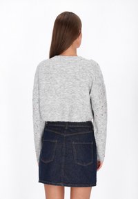 Gehaakte grijze trui met kleurrijke spikkels, cropped ontwerp en lange mouwen, gecombineerd met een high-waisted spijkerrok. Gelaagd materiaal.