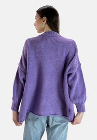 Maglione lavorato a maglia viola con taglio morbido, spalle basse e polsini a coste. Texture morbida con orlo posteriore allentato.