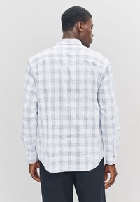 Camicia a maniche lunghe a quadri in toni bianco e azzurro chiaro, con colletto abbottonato, tessuto texturizzato e orlo curvo.