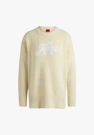 Jasna kremowa sweter o dzianinowym splocie z okrągłym dekoltem, z teksturowanym wykończeniem i białym logo "Hugo" wyraźnie widocznym z przodu.