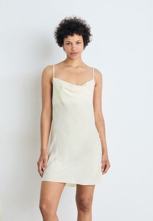 Satin slip dress in pale yellow with a cowl neckline and thin shoulder straps, featuring a smooth texture and knee-length cut.