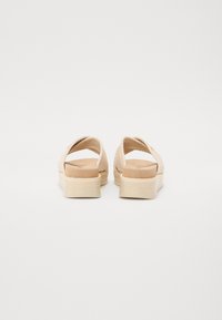 Beige vävda sandaler med en kraftig sula, öppen bak och korsremdesign. Mjuk texturerad fotbädd och lätt konstruktion.