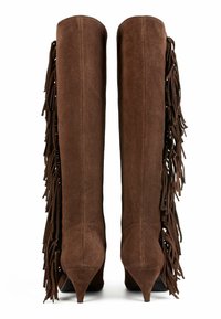 Botas de ante marrón hasta la rodilla con detalle de flecos en el lado exterior y punta afilada, con un tacón delgado en forma de cono.