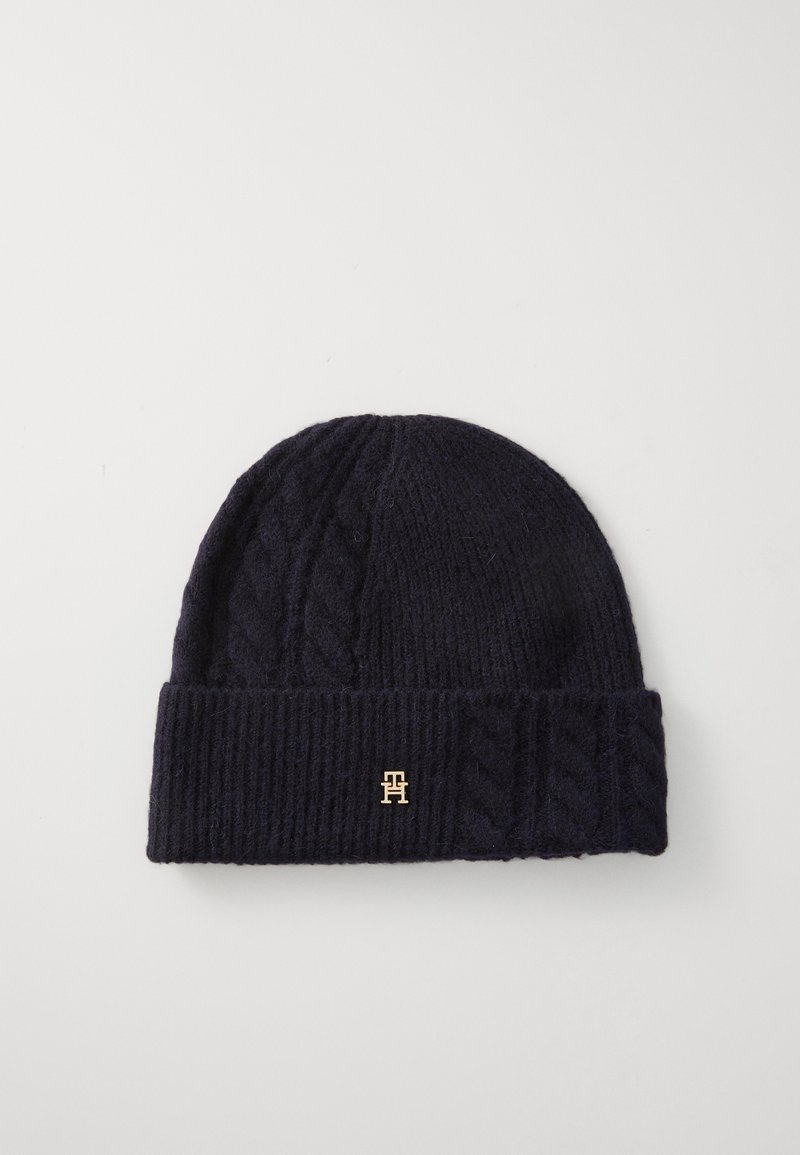 Beanie tricotat în marină, cu un model cu cabluri și un tiv pliat. Prezintă un mic accent cu logo auriu în față. Textură moale.