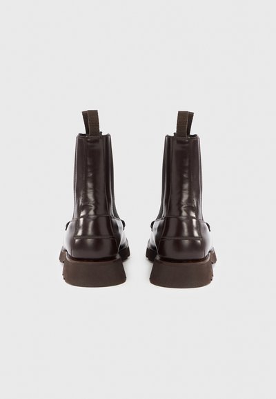 Stivali Chelsea in pelle marrone con finitura liscia, linguetta posteriore e suole di gomma marrone massicce. Design semplice, inserti elastici laterali.