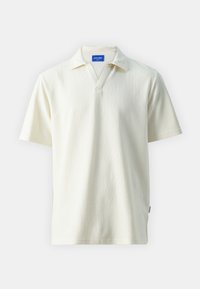 Camisa polo blanca de canalé con escote en V, mangas cortas y superficie texturizada. Presenta una etiqueta azul en el cuello.