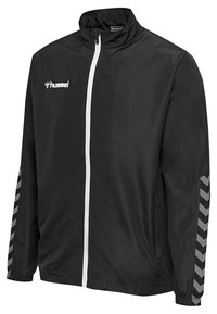 Schwarze Windbreaker-Jacke mit weißem Reißverschluss und Logo, ausgestattet mit grauen Zickzackmuster-Akzenten an den Ärmeln und elastischen Bündchen.