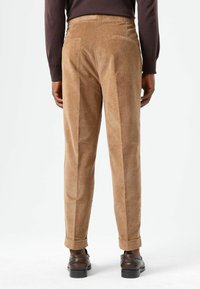Brown corduroy trousers with a straight fit, featuring a waistband, twin back pockets, and rolled cuffs. Smooth texture and light sheen.
