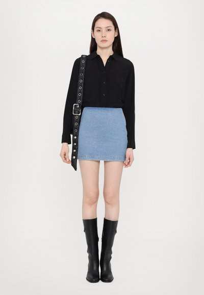 Black button-up shirt with textured front, paired with a light blue denim mini skirt. Model wears knee-high black boots and a studded belt.